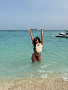 a woman standing in the ocean with her arms up