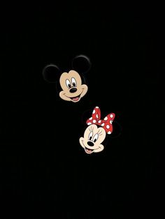 two mickey and minnie mouse heads in the dark