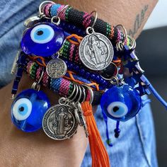 bracelets with evil eyes and charms on each one hand, all in different colors