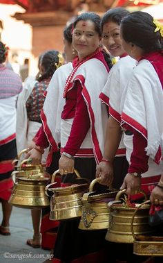 three women in red and white outfits carrying brass pots