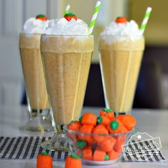 three glasses filled with drinks sitting on top of a table next to candy candies