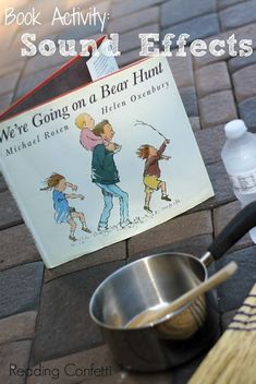 an open book sitting on top of a table next to a metal pan and spoon