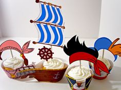 a table topped with cupcakes covered in frosting and pirate themed toppings