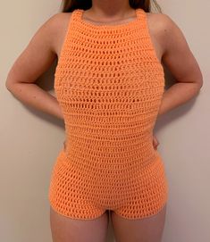 a woman in an orange crochet swimsuit posing for the camera with her hands on her hips