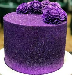 there is a purple cake that has flowers on the top and bottom, sitting on a white plate