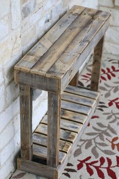 a wooden bench sitting in front of a brick wall next to a red and white rug