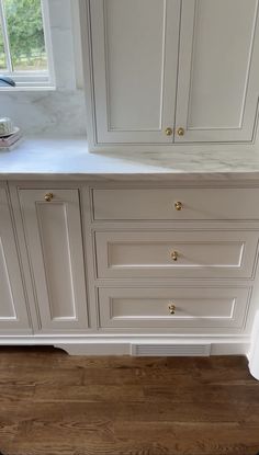 a kitchen with white cabinets and wood floors