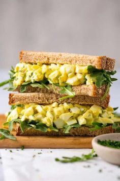 an egg salad sandwich is cut in half on a cutting board