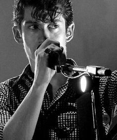 a man holding a microphone up to his mouth while standing in front of a microphone