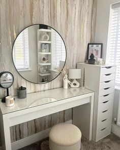 a white desk with a round mirror on it's wall and a stool in front of it