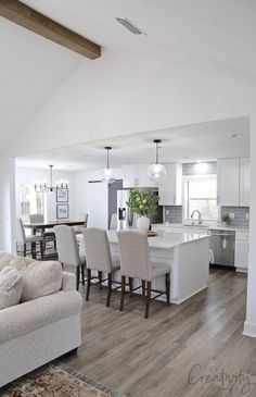 a living room and kitchen area in a house with hardwood floors, white walls and ceilings