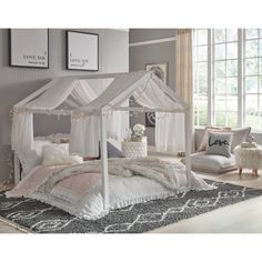 a white canopy bed sitting on top of a wooden floor