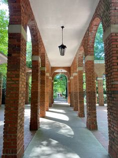 the walkway is lined with brick pillars and lanterns hanging from it's ceilings