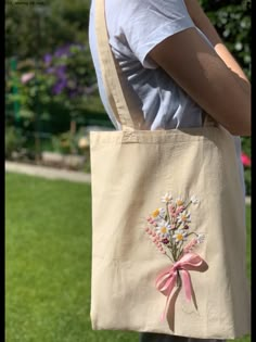 a person holding a bag with flowers on it and a pink ribbon around the handle