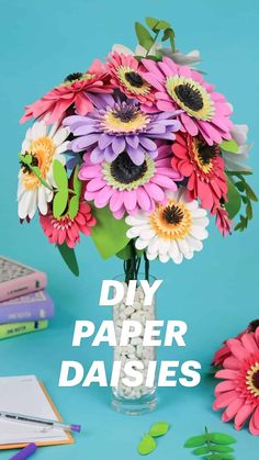 a vase filled with lots of colorful flowers on top of a blue table next to books