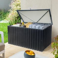 an outdoor storage box with lemons in it on a patio next to a potted plant