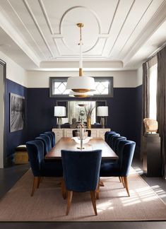 a dining room table with blue chairs and a chandelier hanging from the ceiling