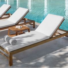 two lounge chairs next to a swimming pool