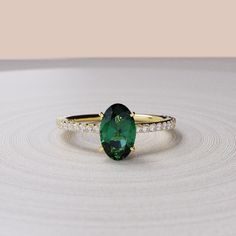 an oval shaped green ring with diamond accents