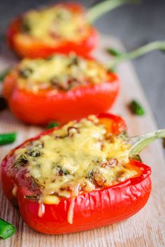 three stuffed red peppers on a cutting board