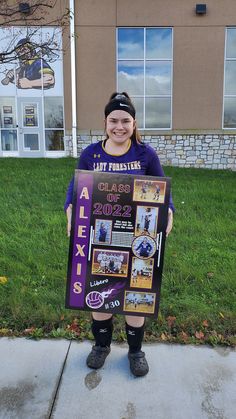 a girl holding up a sign that says alex's class of 2013 on it