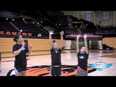 three people standing on a basketball court with their arms in the air and hands up