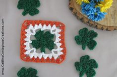 crocheted shamrocks are arranged on a table next to a piece of wood