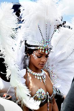 a woman with white feathers on her head and body is standing in front of other people