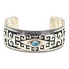 This is part of Chairish’s Costume Jewelry assortment.  Vintage Native American Jacob Kahe cuff bracelet featuring on oval raised turquoise set onto an ornate overlay sterling silver oxidized cuff.  Marked on the back sterling with a KK back-to-back mark for Jacob Kahn.  Interior of the cuff measures 5 1/2" with an additional 1 1/4 " gap for a total circumference of 6 3/4".  Sterling Silver is relatively malleable, thus this cuff is slightly adjustable. Width measures 2.52" straight across the widest part (from wrist bone to wrist bone). Bracelet face measures .94" tall (the face of the bracelet, north to south). Bracelet depth from top to the underside of wrist is 1.97". Bone Bracelet, Bones Bracelet, Native American Turquoise, American Turquoise, Sterling Silver Cuff Bracelet, Sterling Silver Cuff, Late 20th Century, Silver Cuff Bracelet, Silver Cuff