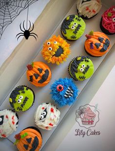 cupcakes decorated to look like monsters and pumpkins are on display in a box