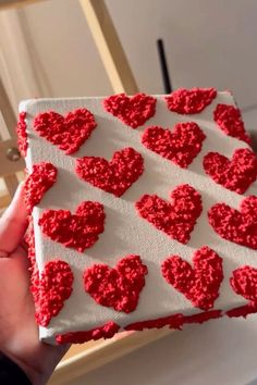 someone is holding up a piece of cake with red hearts on it