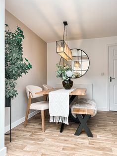 a dining room table with chairs and a bench in front of the mirror on the wall