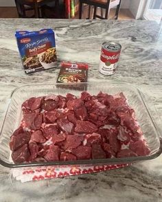 raw meat in a glass baking dish on a kitchen counter next to two boxes of frozen food