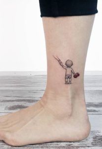 a small tattoo on the ankle of a person with a heart in his hand and an arrow