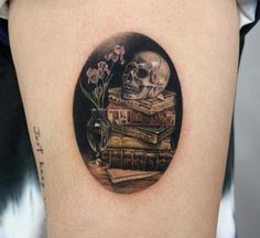 a skull sitting on top of a pile of books next to a vase with flowers