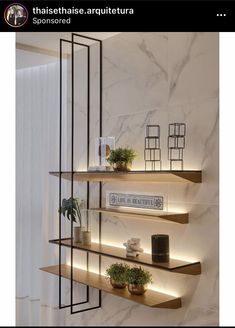 three shelves with plants and pictures on them in a room that has marble walls and flooring