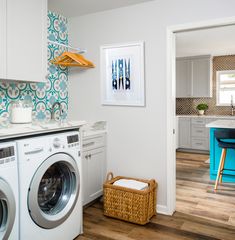 a washer and dryer sitting in a room next to a kitchen with blue accents