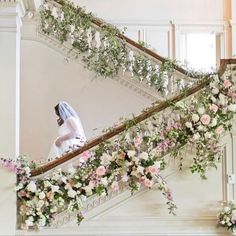 the bride is walking down the stairs in her wedding dress and veil with flowers all over it