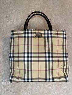 Vintage Burberry Nova Check top handle tote. Authentic. Preloved. Very good condition. Classic Nova Check canvas body. Brown leather handles. Slight discolouration around Burberry label on the outside. Magnetic snap closure. Canvas lined on the inside. One zipper interior pocket. Comes with original dust bag. Made in Italy. Measures 28.5cm length x 10cm width x 26cm height. Handles drop 10cm. Burberry Top, Burberry Purse, Check Tops, Purse Vintage, Top Handle Bags, Vintage Burberry, Leather Handles, Leather Handle, Purses And Handbags