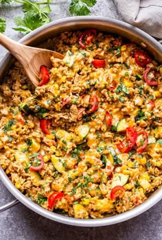 southwest turkey vegetable and rice skillet in a pan with a wooden spoon on the side