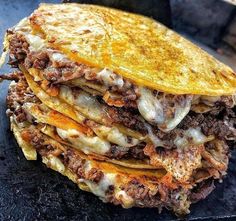 a stack of quesadillas sitting on top of a black pan covered in cheese