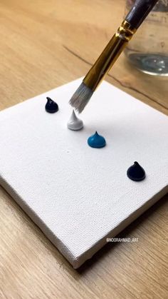 an artist's paintbrush is being used to paint rocks on a piece of canvas