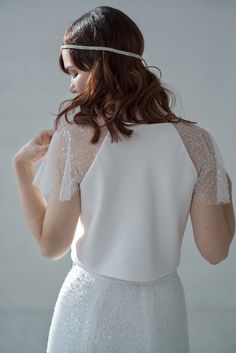 This crop top features a double bias cut satin bodice (no bust darts!) and wide, sparkly beaded raglan sleeves and a crew neck. We recommend strapless bra underneath this wedding crop top. Only available in the shown IVORY color. Please be aware that your veil or other items can stick to this top's sleeves due to sequins, it can also stick together a little bit at times, and you may lose some beads or sequins while wearing it - it is perfectly normal and won't be noticeable in grand scheme of th Elegant Cropped Crop Top For Wedding, Evening Crop Top With Sheer Sleeves, Elegant Embellished Wedding Crop Top, Elegant White Crop Top For Wedding, Elegant Cropped Crop Top With Sheer Sleeves, Elegant Lace Bodice Top For Wedding, Elegant Wedding Tops With Lace Bodice, Fitted Short Sleeve Top For Wedding, Fitted Wedding Top With Sheer Bodice