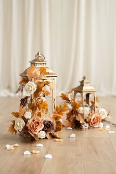 an arrangement of flowers and candles on a wooden floor with petals scattered around the table