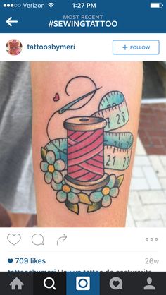 a tattoo with a spool of thread and measuring tape