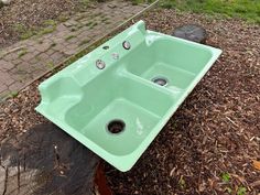 a green sink sitting on top of a tree stump next to a brick walkway and grass