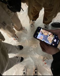 a group of people standing next to each other in the snow looking at a cell phone