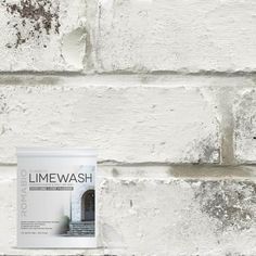 a can of lime wash sitting on top of a white brick wall