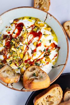 a bowl filled with food next to some bread