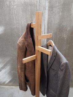 a coat rack with two coats hanging from it's sides and a suit jacket on the other side